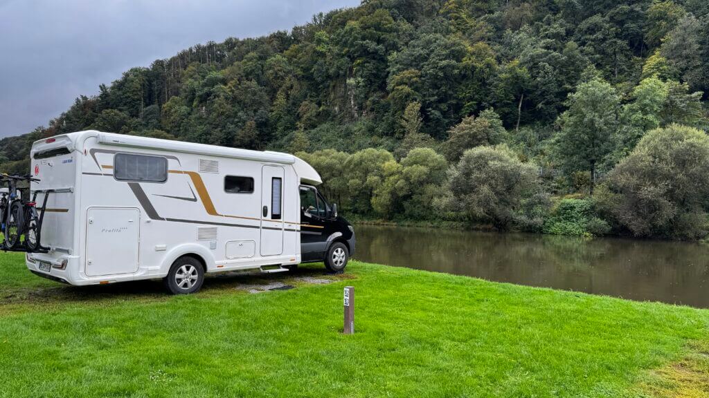 „Unser Rollcontainer mit Klo und Küche auf einer Wohnmobiltour, abgestellt vor malerischer Naturkulisse.“