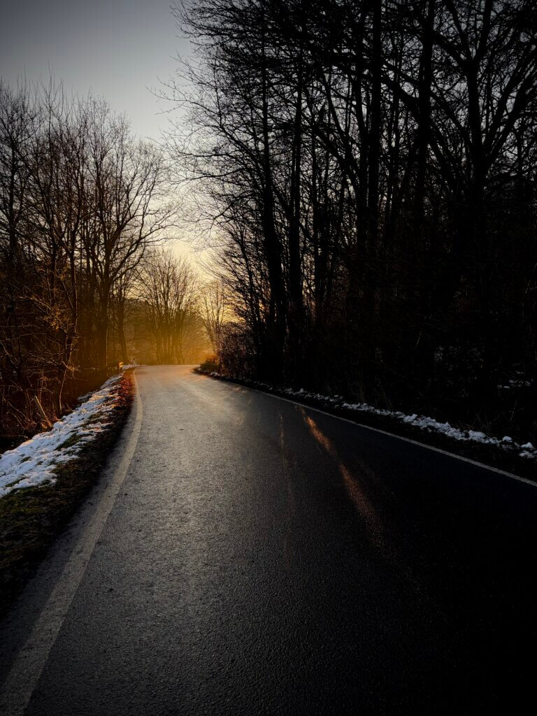 Einsame Landstraße in diesigem Licht der Abendsonne
