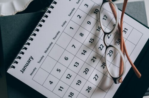 Nahaufnahme eines Tischkalenders für Januar mit einer Brille, die teilweise darauf liegt.