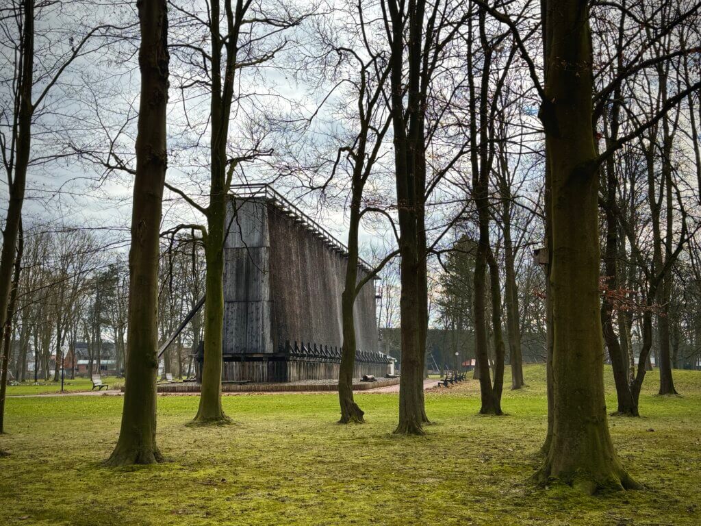 Das Bild zeigt Bäume im Vordergrund und ein Gradierwerk im Hintergrund im Kurpark von Bad Westernkotten.