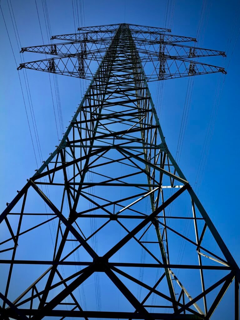 Foto einer Hochspannungsleitung von unten nach oben fotografiert vor blauem Himmel im Ittertal