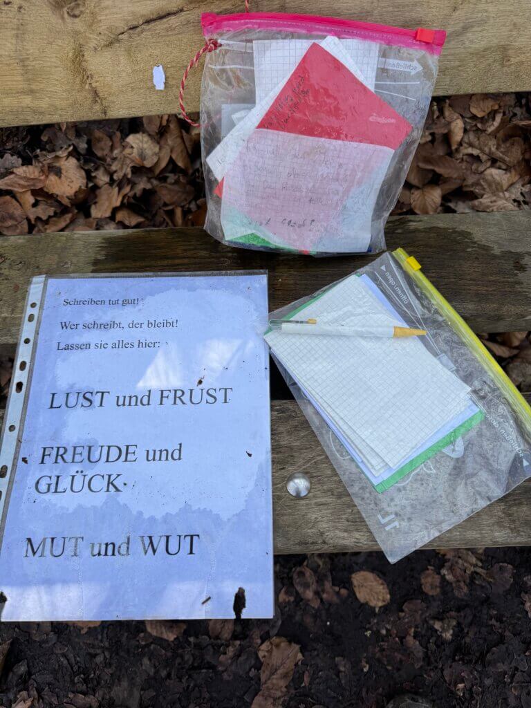 Kunst unterwegs. Auf einer Bank im Ittertal liegen Zettel in einer Klarsichfolie, die dazu auffordern eine Nachricht zu hinterlassen.