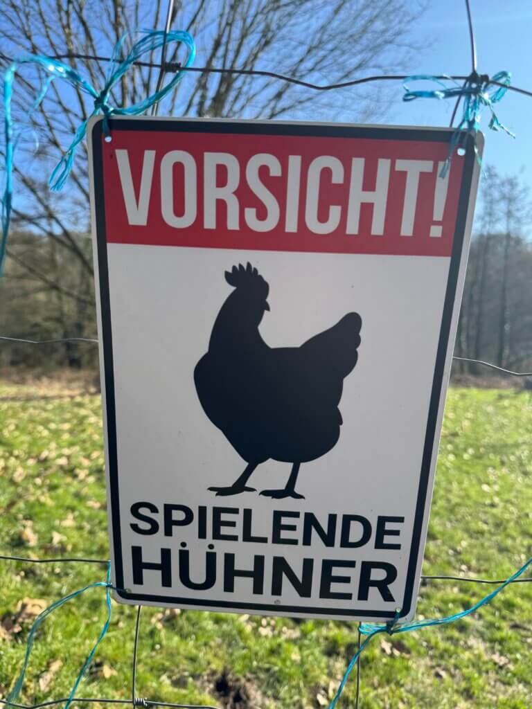 Ein Warnschild mit der Aufschrift Vorsicht spielende Hühner im Ittertal in Haan