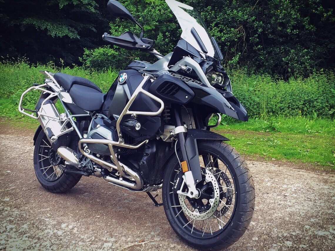 BMW R 1200 GS Adventure Motorrad auf einem Waldweg – geländetaugliche Reise-Enduro mit Sturzbügeln, Windschild und Speichenrädern für Offroad-Abenteuer.