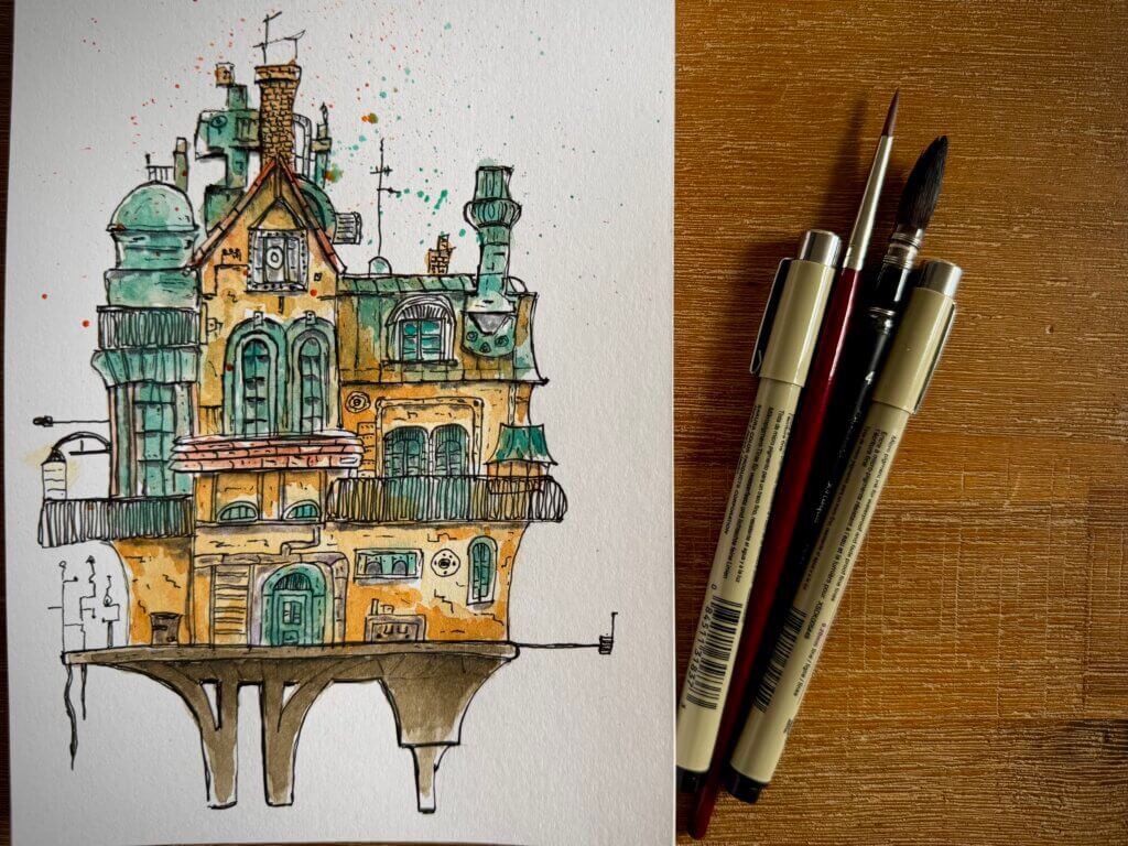Detailreiche Urban-Sketching-Zeichnung eines fantasievollen Hauses in Aquarell und Fineliner – daneben Stifte und Pinsel auf Holztisch – kreatives Architekturmotiv, handgezeichnet, inspiriert von Reiseeindrücken und künstlerischer Leidenschaft.