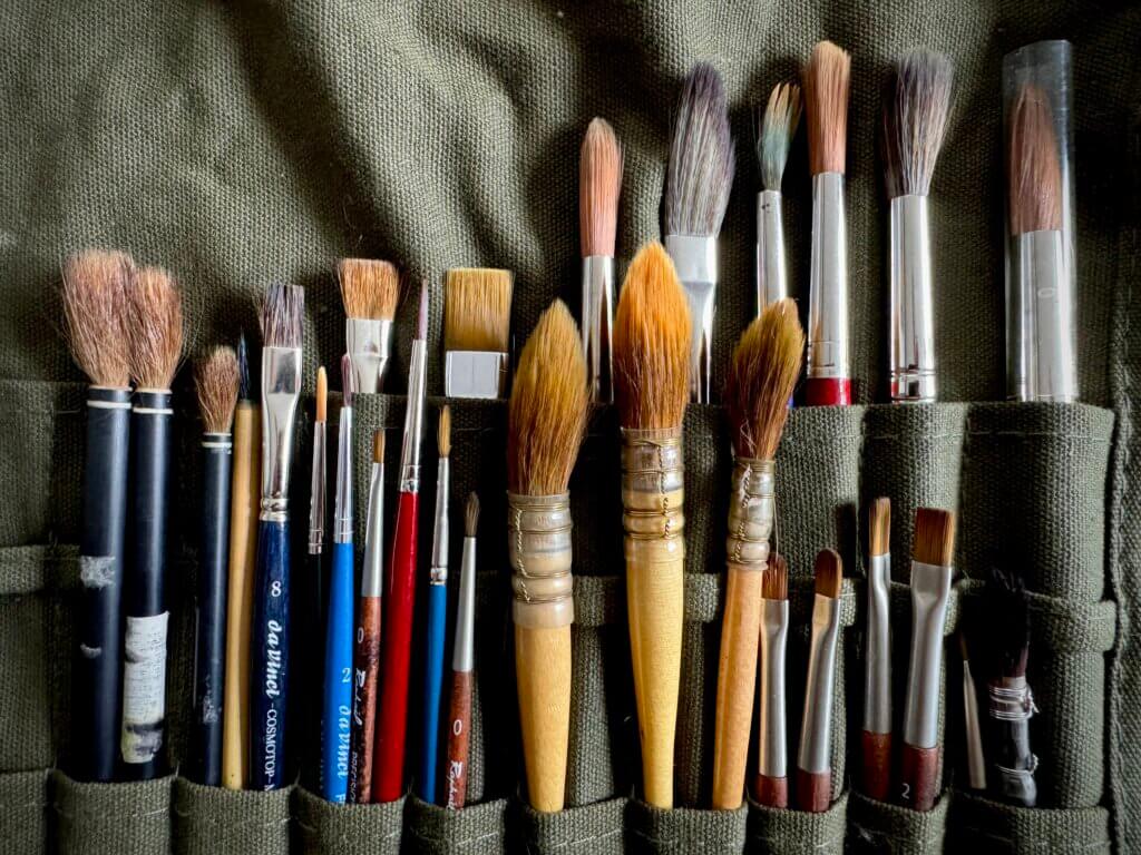Vielfältige Sammlung hochwertiger Künstlerpinsel in Leinenrolle – perfekt für Aquarell, Acryl und Urban Sketching – Symbol für Kreativität, Handwerk und künstlerische Leidenschaft im Ruhestand. Kreativanfall