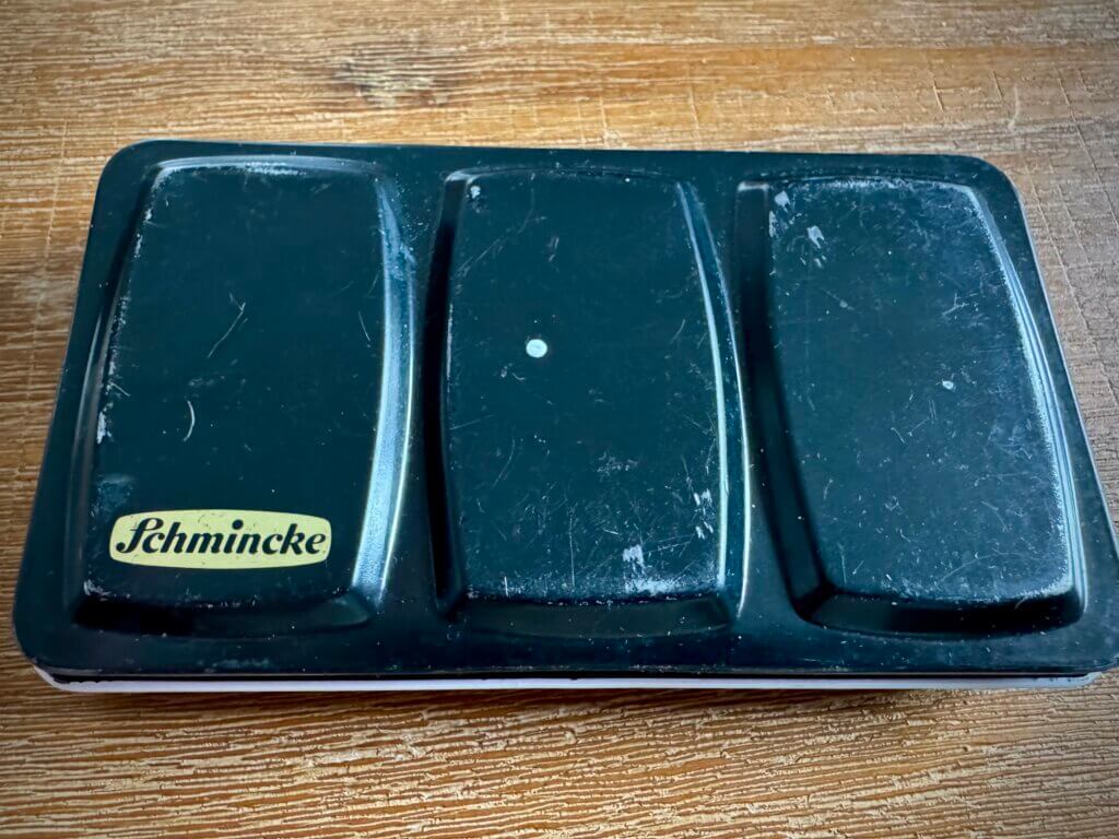 Vintage Aquarellkasten von Schmincke – robuste Metallbox mit Patina und Charme, Symbol für hochwertige Künstlerfarben und kreative Tradition über Generationen hinweg.