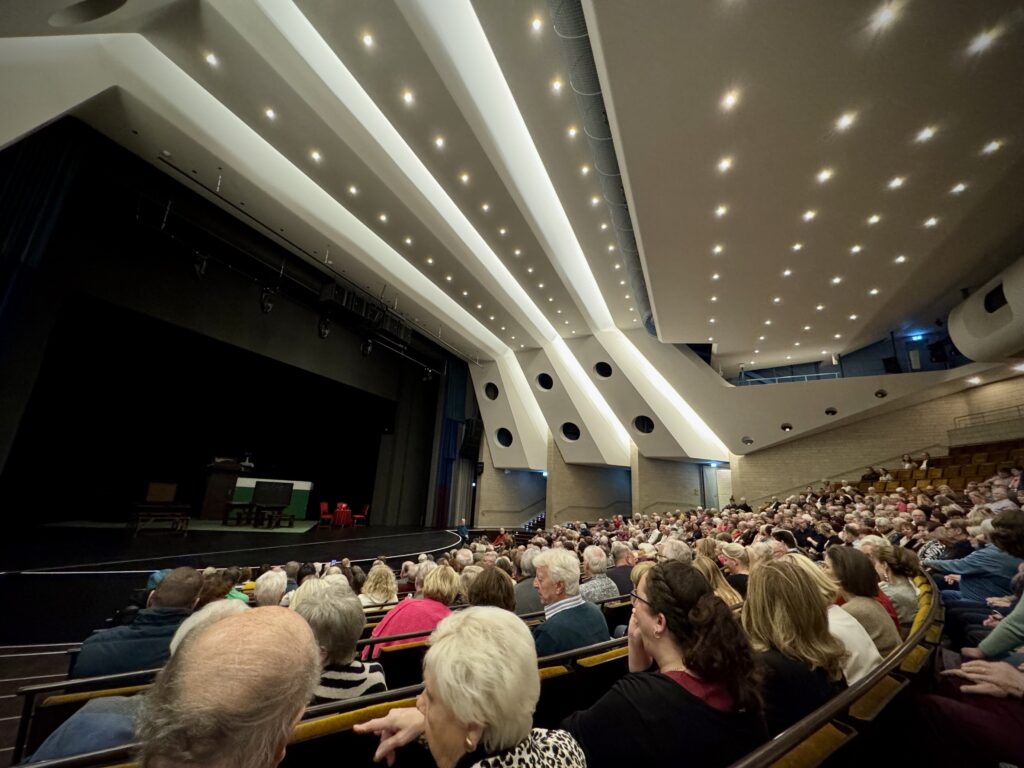 Großer Theatersaal im Forum Velbert mit moderner Deckenkonstruktion, gefüllten Zuschauerrängen und beleuchteter Bühne, bereit für eine Theateraufführung oder Kulturveranstaltung.