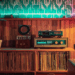 Stilvoll eingerichtetes Retro-Wohnzimmer mit Mid-Century-Möbeln, Vintage-Plattenspieler, Vinylregal und farbiger LED-Wandbeleuchtung – nostalgisches Interior Design mit warmem Holz und dekorativen Details. Dienstags Drabble