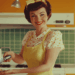 Symbolbild für Muttertag mit Retro-Charme: Frau in gelber Schürze mit Käsehobel. Muttertag im Altenheim