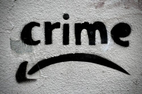 Schablonengraffiti mit dem Wort “crime” und geschwungenem Pfeil auf rauer Hauswand. Streettypografie