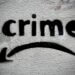 Schablonengraffiti mit dem Wort “crime” und geschwungenem Pfeil auf rauer Hauswand. Streettypografie