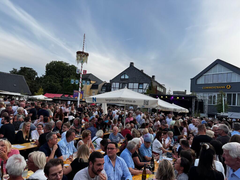 Gut besuchtes Weinfest in Velbert mit Bierbänken, Menschenmengen und Bühne unter freiem Himmel
