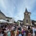 Weinfest in Velbert mit Menschenmengen vor Kirchturm bei Sonnenschein.