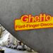 Aufkleber mit dem Schriftzug „Ghetto Fünf-Finger-Discount“ auf grauem Verkehrsschild in urbaner Straße. Fünf-Finger-Philosophie.