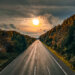 Leere Autobahn im Licht der untergehenden Sonne, umgeben von bunt gefärbtem Herbstwald – stimmungsvolles Foto einer herbstlichen Reise in den Ruhestand.