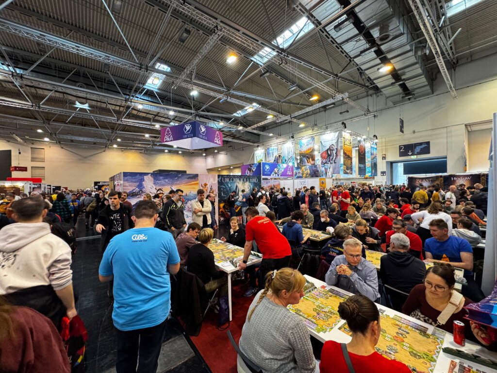 Gemütliche Spielrunden bei Deep Print Games auf der SPIEL Essen Messe – Familien, Freunde und Neugierige an Probiertischen.
