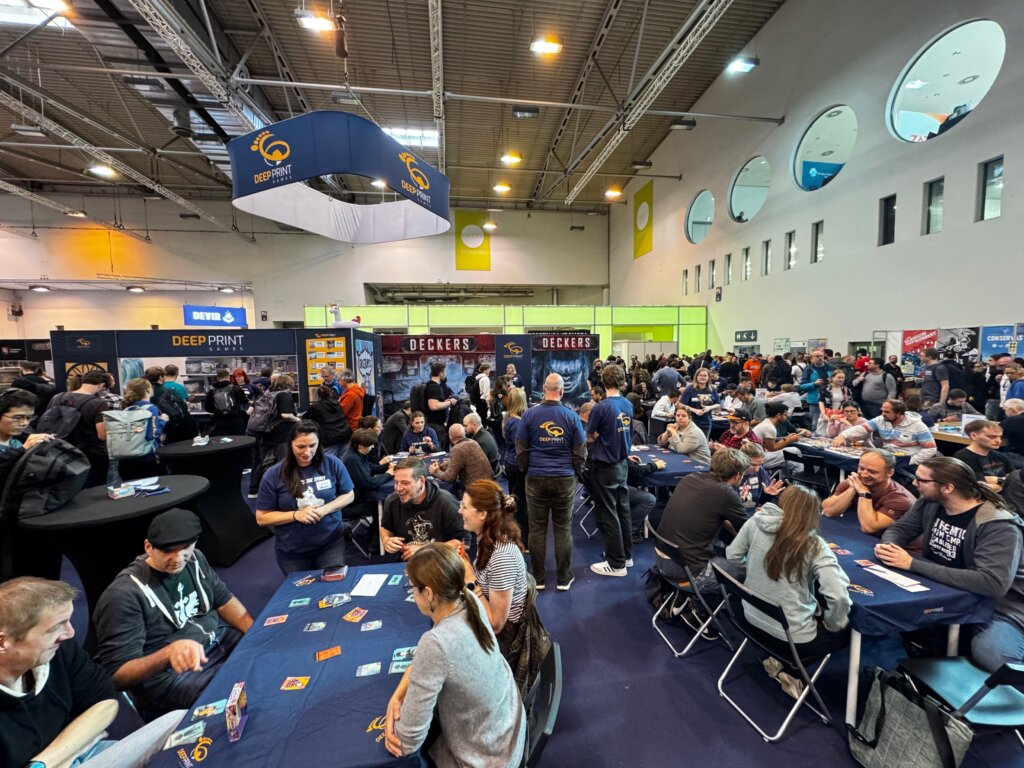 Spielebegeisterte testen Neuheiten auf der SPIEL Essen Messe – dichtes Gedränge, volle Tische, bunte Verlagsstände.