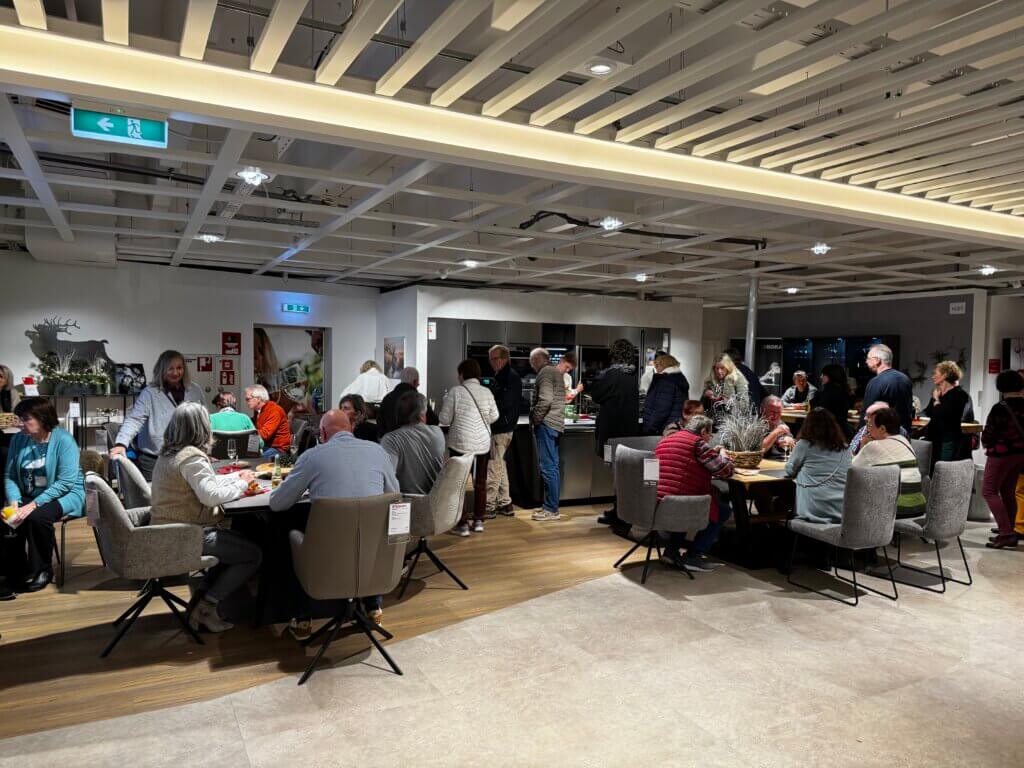 Theateraufführung im Möbelhaus Rehmann Velbert mit Publikum in der Küchenabteilung, Zuschauer sitzen an Ausstellungs-Esstischen während der Jubiläumsveranstaltung 50 Jahre Gebietsreform. Monatsrückblick November