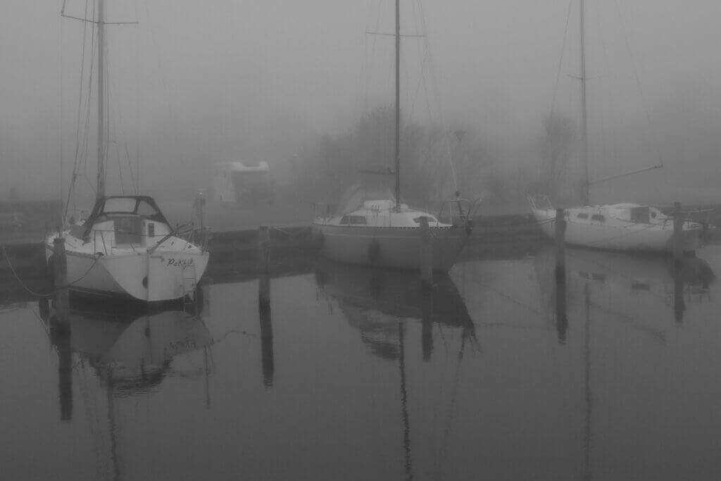 Drei Segelboote liegen im nebligen Hafen von Sneek, im Hintergrund ist ein Wohnmobil zu sehen.