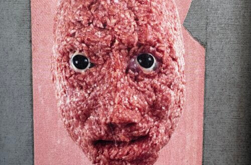 Ein an eine graue Wand geklebtes Plakat zeigt ein surreal wirkendes Gesicht, das vollständig aus rohem Hackfleisch besteht. Die Augen sind glänzend und realistisch, der Hintergrund rosa, das Papier leicht beschädigt. Das Motiv wirkt irritierend und humorvoll zugleich. Urbane Sticker Kunst