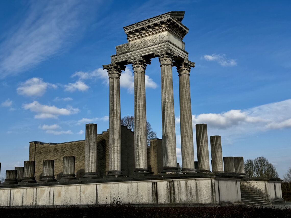 Der rekonstruierte Hafentempel im archäologischen Park Xanten. Die Tempelanlage mit Säulenreihen steht auf einer Plattform vor blauem Winterhimmel.
