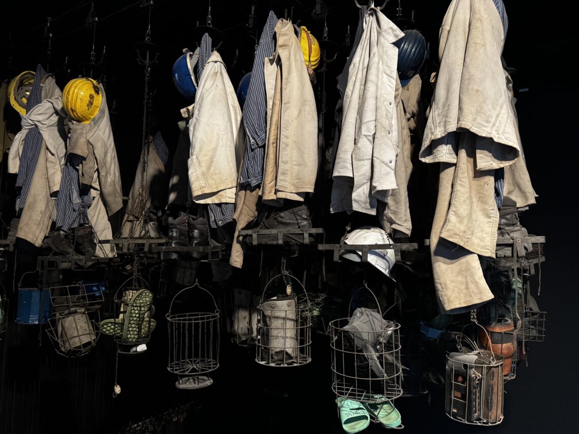 Traditionelle Bergmannskleidung und Ausrüstung, die an einer Wand in der Ausstellung des Deutschen Bergbau-Museums Bochum präsentiert wird.