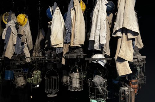 Traditionelle Bergmannskleidung und Ausrüstung, die an einer Wand in der Ausstellung des Deutschen Bergbau-Museums Bochum präsentiert wird.