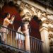 Zwei Frauen fotografieren von einem Balkon mit verzierter Fassade – Streetfotografie in warmen Farben und architektonischen Details
