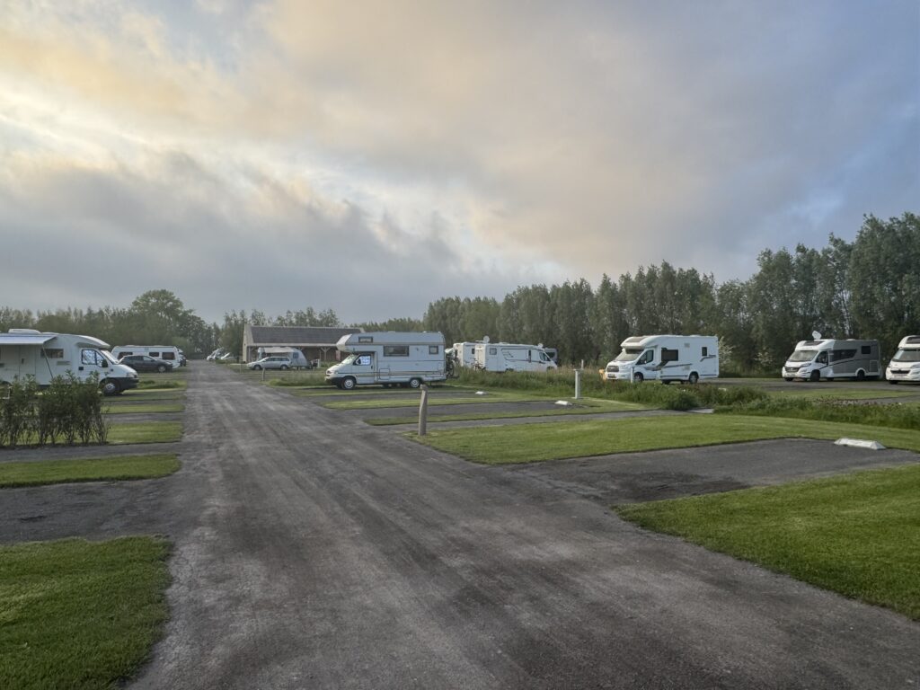 Wohnmobile auf dem Campingplatz Gentele am Ortsrand von Brügge bei wechselhaftem Abendhimmel.
