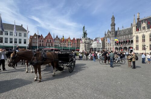 Marktplatz von Brügge mit historischen Fassaden, Pferdekutsche und Besuchern in der Altstadt.