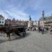 Marktplatz von Brügge mit historischen Fassaden, Pferdekutsche und Besuchern in der Altstadt.