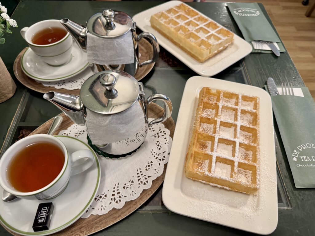 Tee und belgische Waffeln mit Puderzucker in einem Café in der Altstadt von Brügge.