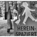 Streetfotografie in Wuppertal in Schwarzweiß: Ein roter Aufsteller mit einer Silhouette eines Kindes, einer Gans und der Aufschrift Hereinspaziert steht im Vordergrund. Dahinter läuft ein Passant in einem karierten Mantel vorbei, dessen Oberkörper abgeschnitten ist.