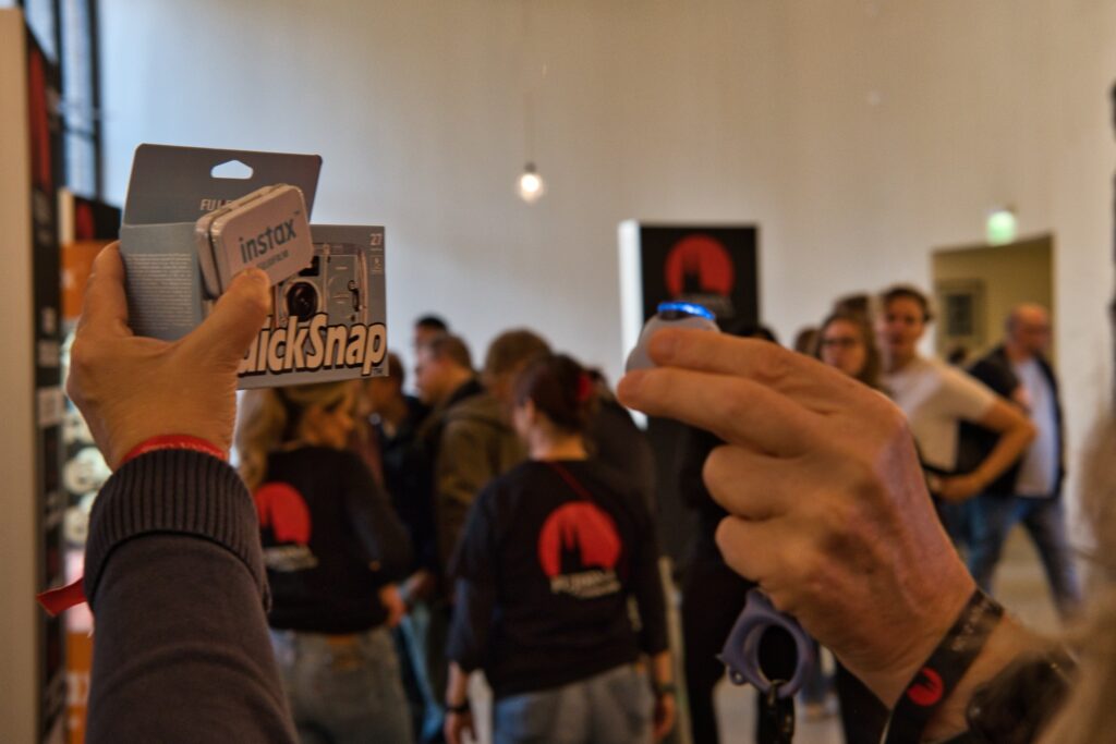 Nahaufnahme einer Fujifilm QuickSnap Einwegkamera in der Hand eines Besuchers der Fujikina.