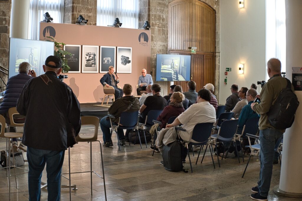 Vortrag auf der Bühne der Fujikina Köln 2026 mit Publikum im Innenraum.