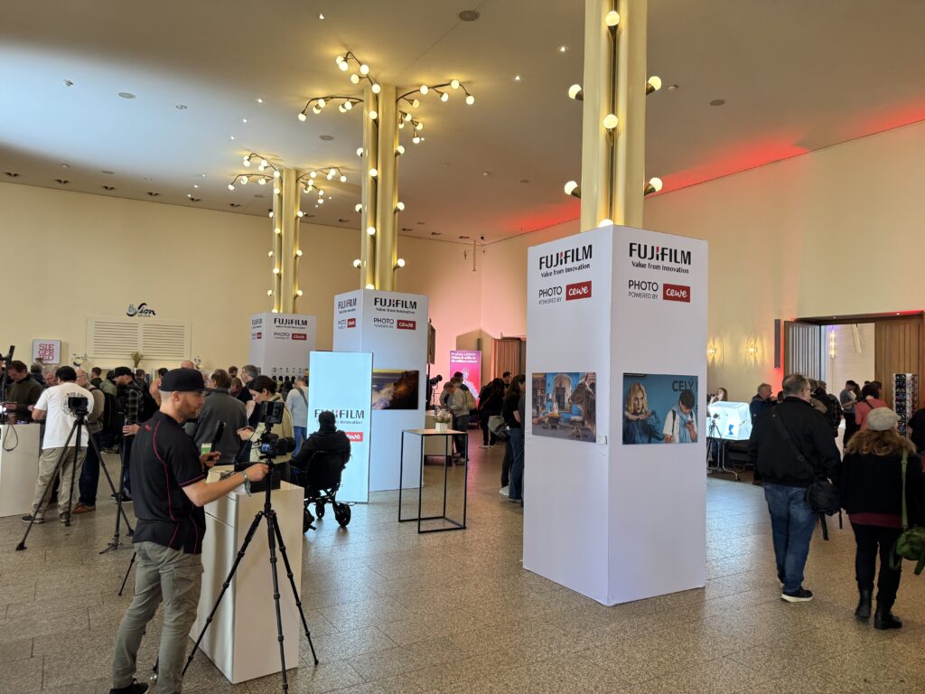 Besucher im Foyer des Gürzenich zwischen großen Wänden mit Fujifilm- und CEWE-Fotodrucken.