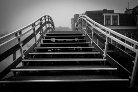 Holztreppe mit weißem Geländer führt in dichter Nebelwand zwischen Altstadthäusern.