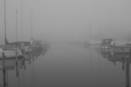Dichtes Nebelwetter über der ruhigen Marina de Dome in Sneek mit festgemachten Segelbooten auf beiden Seiten eines Kanals.
