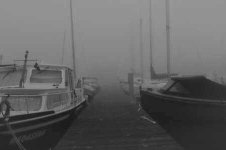 Boote liegen an einem Holzsteg in der Marina de Dome in Sneek der im dichten Nebel verschwindet – das Wasser ist glatt und dunkel.