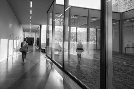 Museumskorridor mit Glasfront und Spiegelungen, Besucherin im Gegenlicht am Fenster des Folkwang Museums