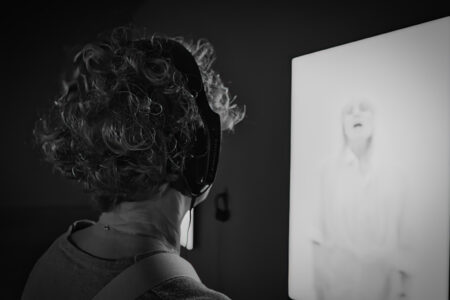 Museumsbesucherin betrachtet Schwarz-Weiß-Porträt, lockige Haare im Profil vor dunkler Wand, Folkwang Museum Essen