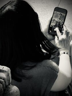 Frau von oben fotografiert, blickt auf Smartphone-Display mit Foto darauf, Schwarzweiß-Streetfotografie Sevilla, Vogelperspektive