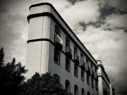 Weißes Wohngebäude in Sevilla mit markanter runder Ecke und Wäsche auf einem Balkon, bewölkter Himmel, Schwarzweiß-Architekturaufnahme