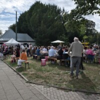 Besucher auf Bierbänken auf der Wiese vor einer Bude beim Tag der Trinkhallen in Essen-Bredeney