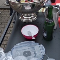 Nahaufnahme einer Punschbowle mit Sektflasche und Gläsern auf einem Budentisch"